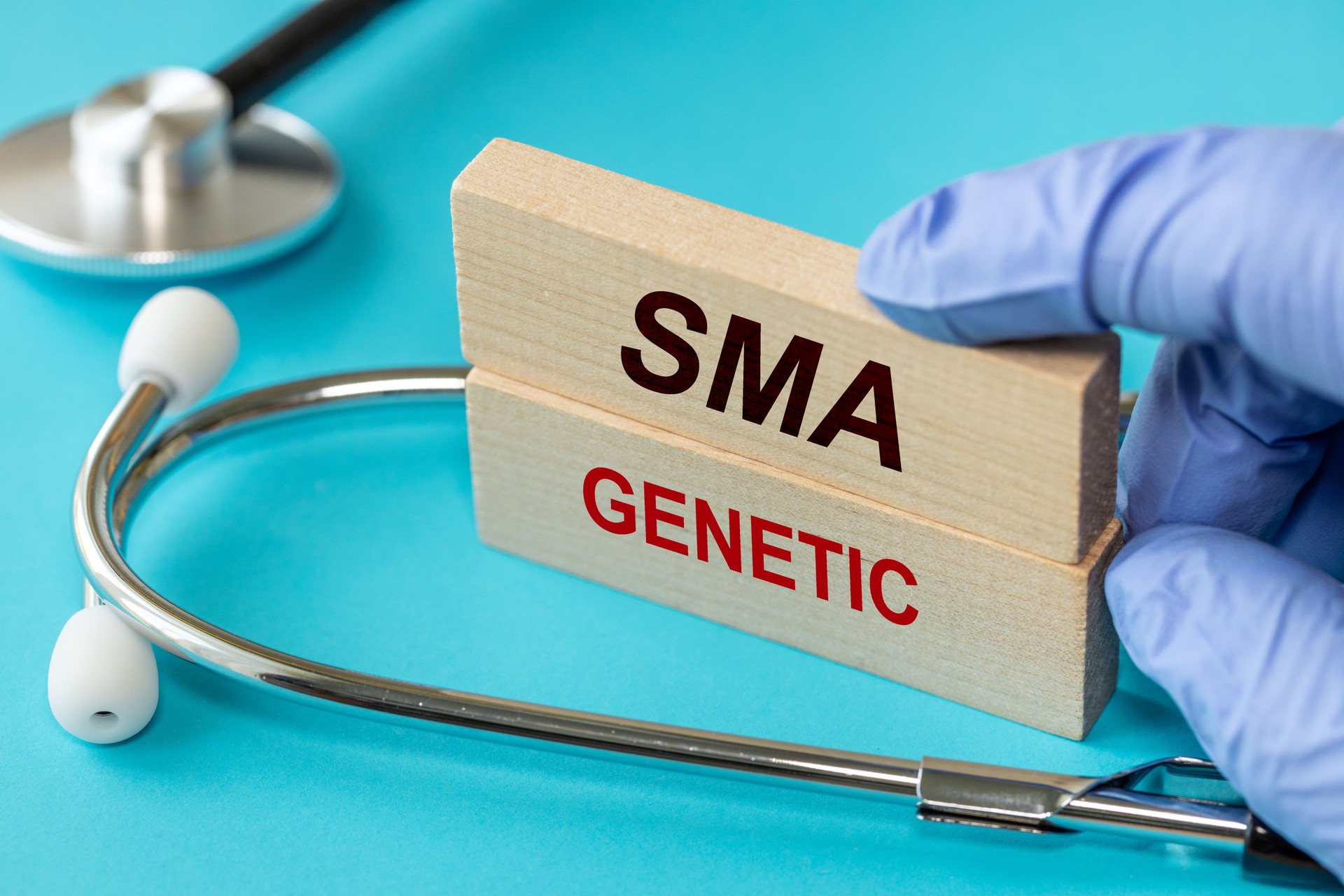 SMA disease, Doctor shows wooden blocks with words SMA Genetic. spinal muscular atrophy. Doctor's stethoscope, Beautiful blue background. Health concept